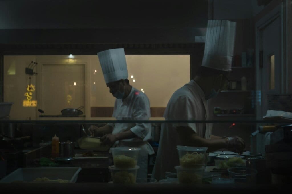 Two Chefs Are Preparing Food In A Kitchen