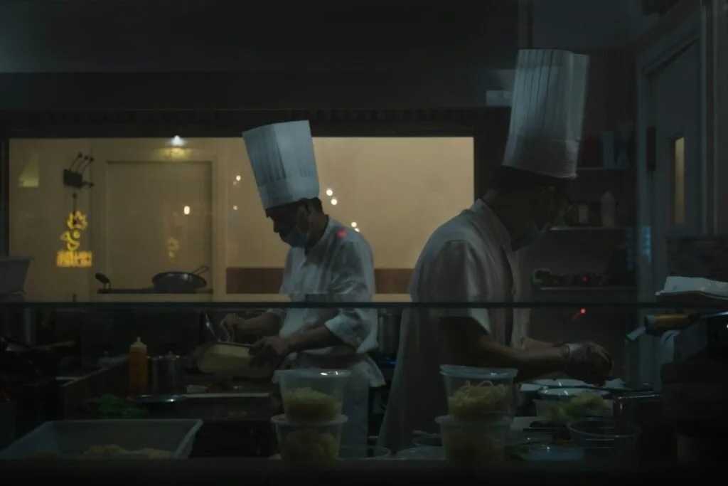 Two Chefs Are Preparing Food In A Kitchen