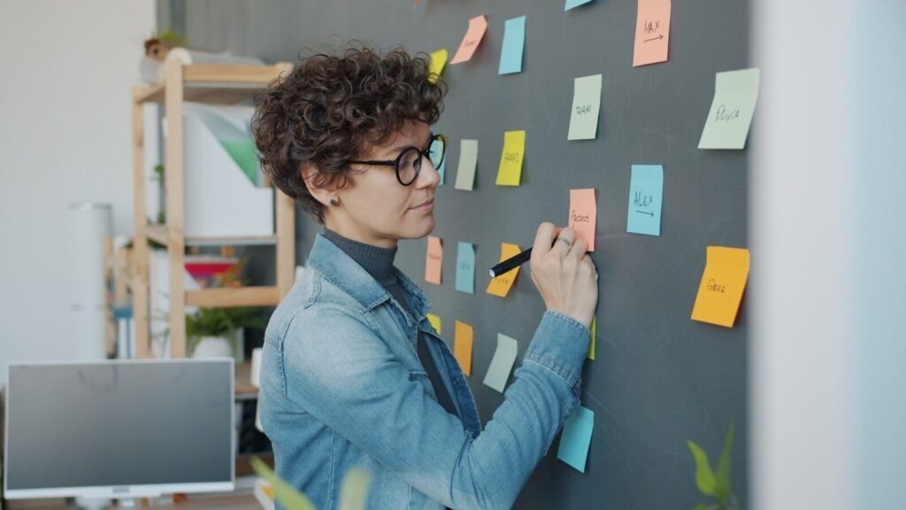 Woman Writing On Sticky Notes On A Wall.