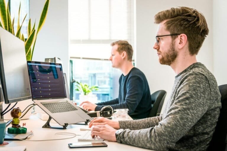 Man Sitting On Chair Wearing Gray Crew-Neck Long-Sleeved Shirt Using Apple Magic Keyboard