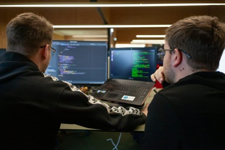 Two Men Sitting In Front Of A Laptop Computer