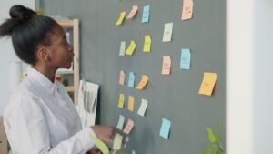 Young woman reviewing colorful sticky notes on wall.
