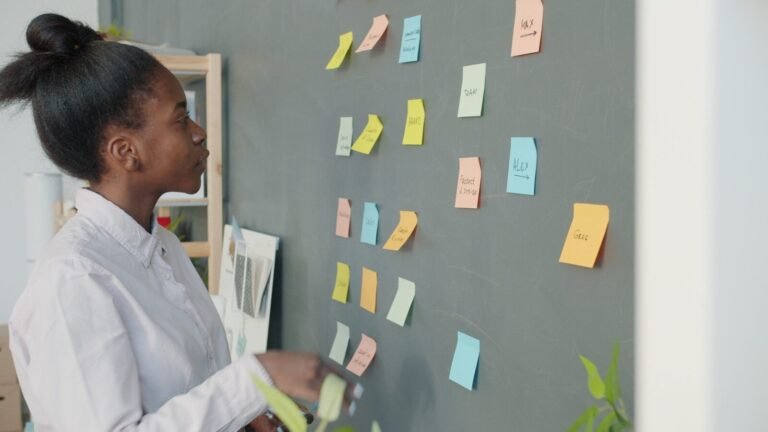 Young Woman Reviewing Colorful Sticky Notes On Wall.